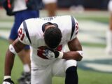 Football player in uniform kneeling before a game, displaying focus and determination.