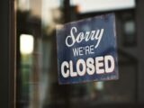 Sorry we're closed signage hanged on glass door